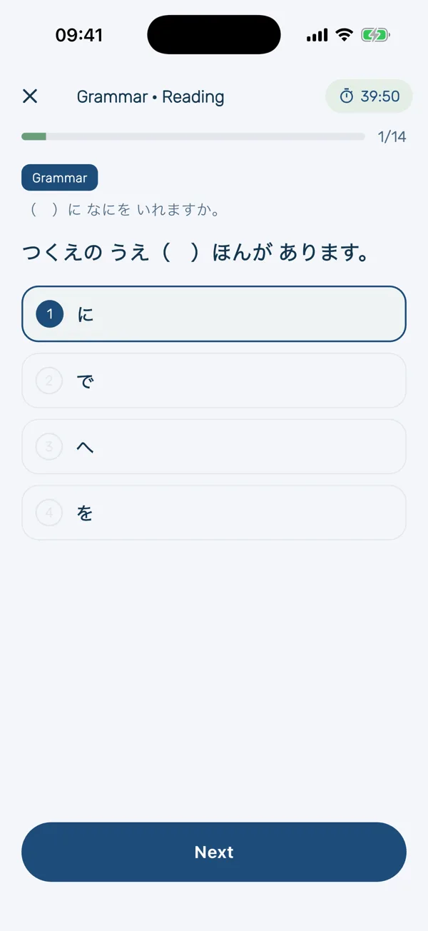 A timed HeyShima mock exam, question 1 of 14 with 39 minutes left: a grammar question asking which particle completes つくえの うえ( )ほんが あります, with に selected